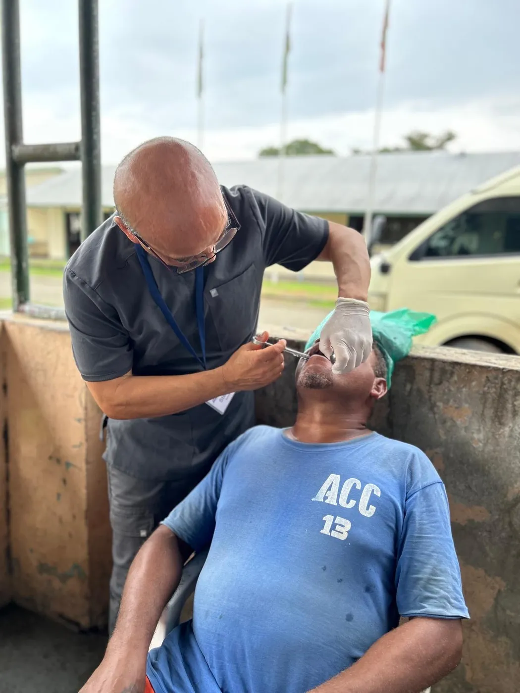 Dr. Steve Chang treating a seated patient’s teeth outdoors